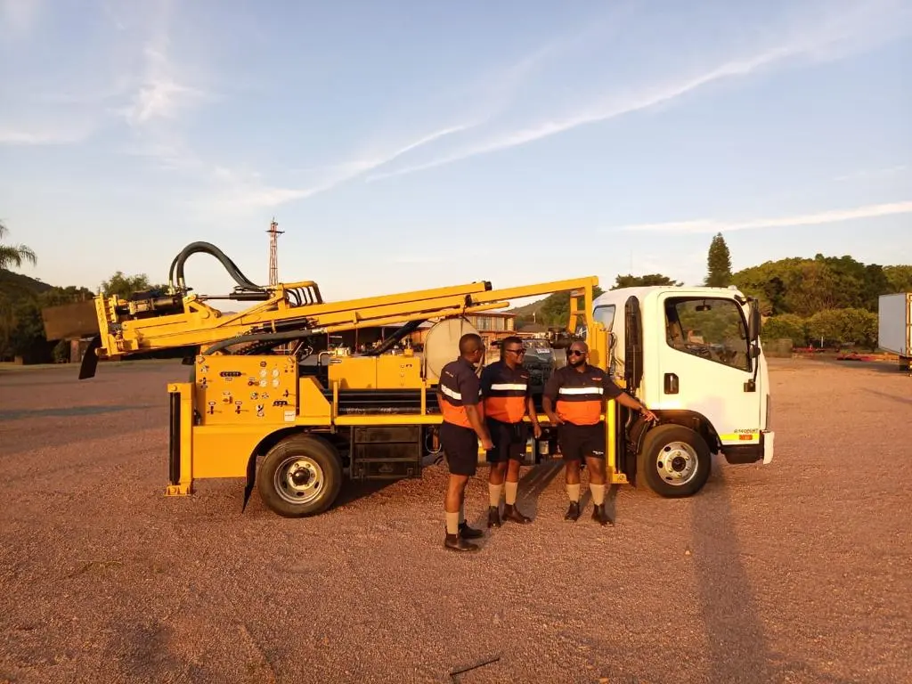 Drillbuilders crew with a completed truck-mounted drilling rig at handover